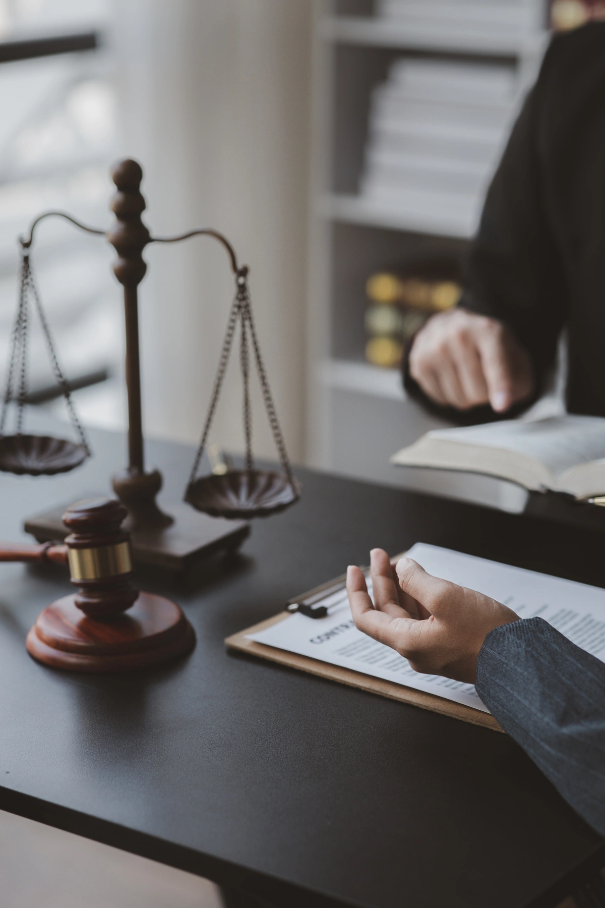 Un avocat consulté pour des conseils juridiques, avec la balance de la justice et un marteau de juge sur le bureau, symbolisant l'impartialité et l'équité en droit public.