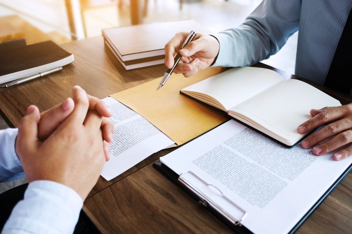 Un avocat discutant d'un dossier juridique avec un client, avec des documents et un stylo sur la table, représentant les services juridiques offerts en droit public.