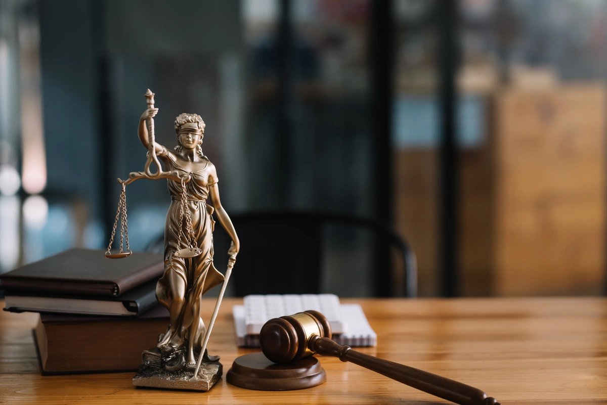 Statue de la justice sur un bureau avec marteau de juge, symbolisant l'équité et la législation en matière de droit de l'urbanisme et de développement territorial.