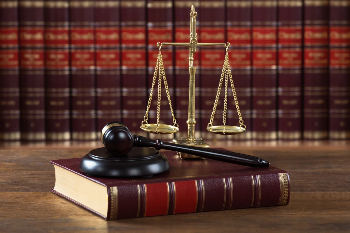 Balance de la justice et marteau de juge posés sur un livre de droit, symbolisant l'autorité et l'équilibre dans le système judiciaire, essentiels au rôle d'un avocat.